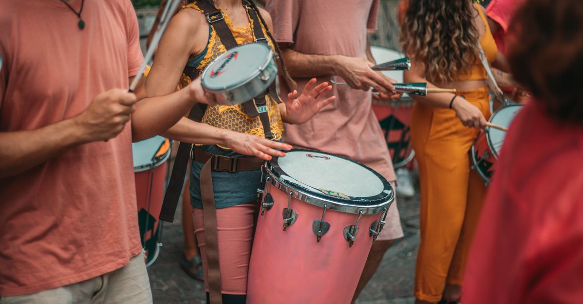 Vibrant street parade with musicians playing various drums and percussion instruments.